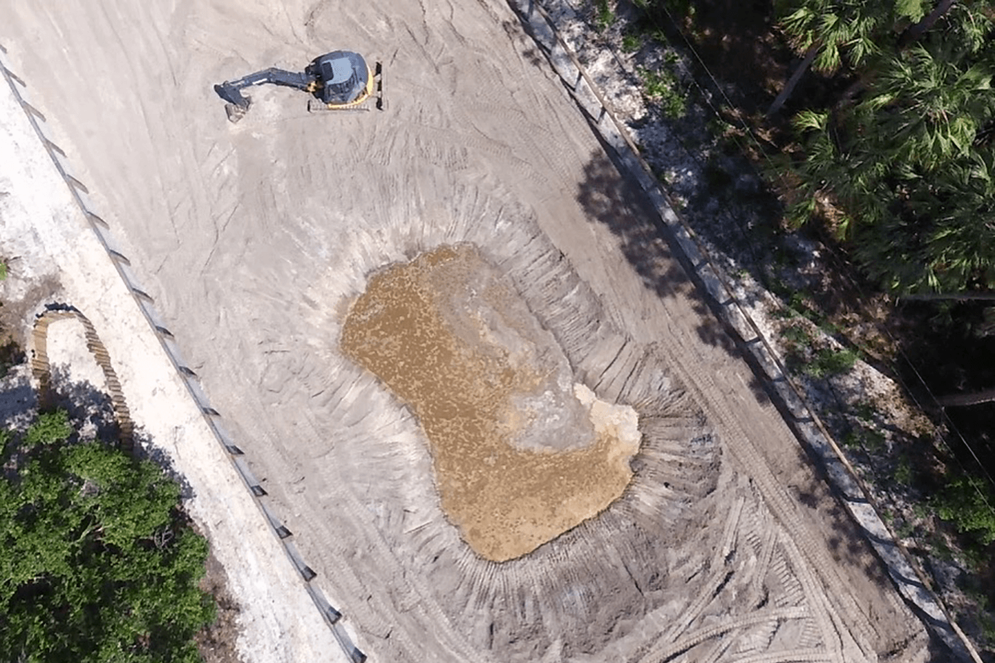 Aerial picture of a finished pond with an excavator next to it
