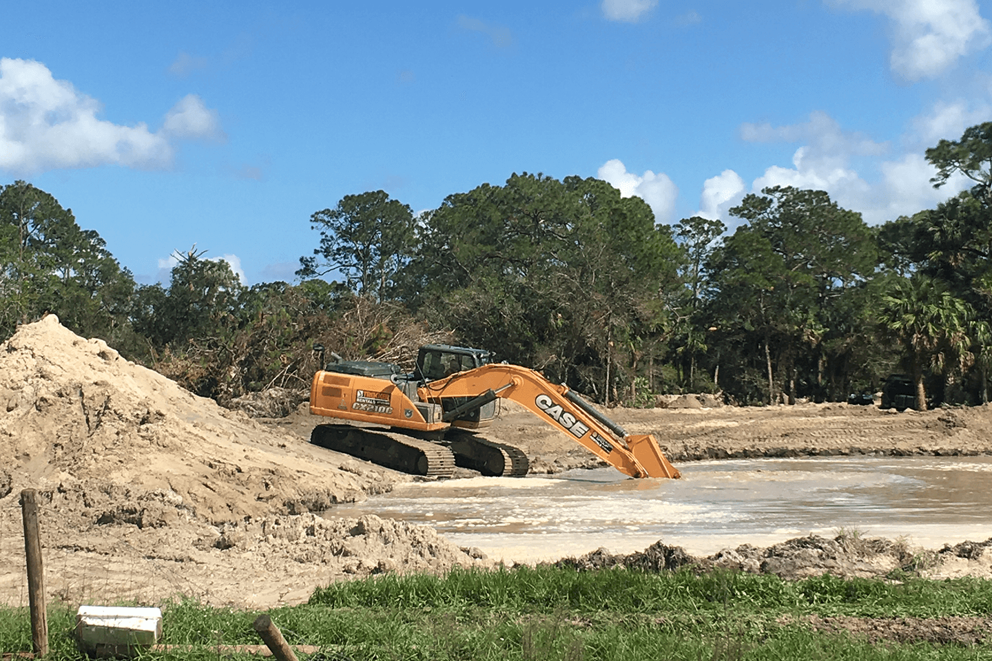 Case excavator digging dirt out of a pond