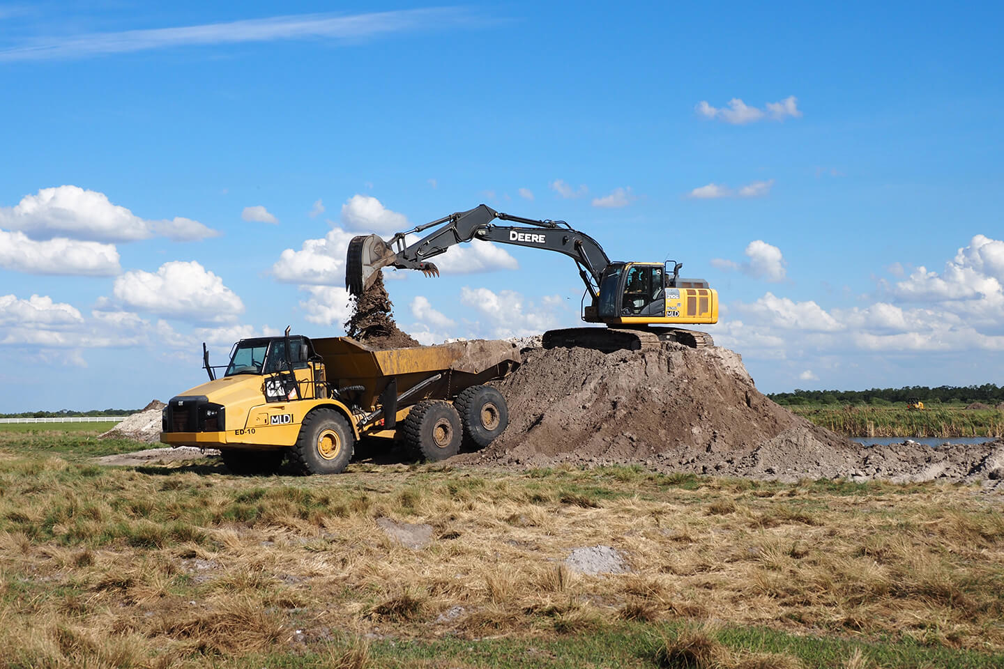 John Deere excavator dumping dirt into a dump truck