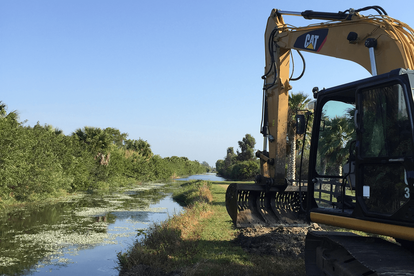 Cat excavator sitting next to a canal